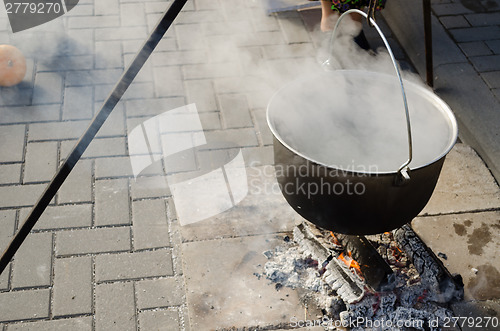 Image of pot with food on metal rods vaporize on fire 