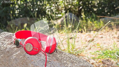 Image of Bright red wired headphones on the rock