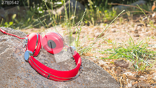 Image of Vivid red wired headphones on the stone