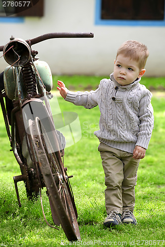 Image of 2 years old curious Baby boy walking around the old bike 