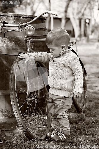 Image of 2 years old curious Baby boy walking around the old bike