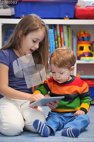 Image of Girl with her little brother fun using a digital tablet computer