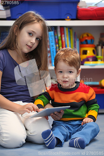 Image of Girl with her little brother fun using a digital tablet computer
