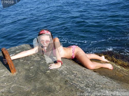 Image of The sexual girl lays on a wharf on a background of the sea