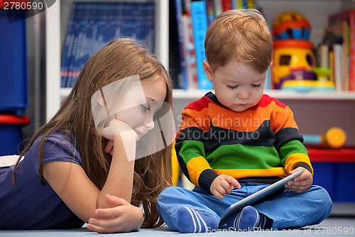 Image of Girl with her little brother fun using a digital tablet computer