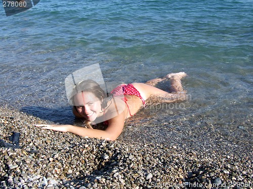 Image of The sexual girl lays on a pebble on seacoast