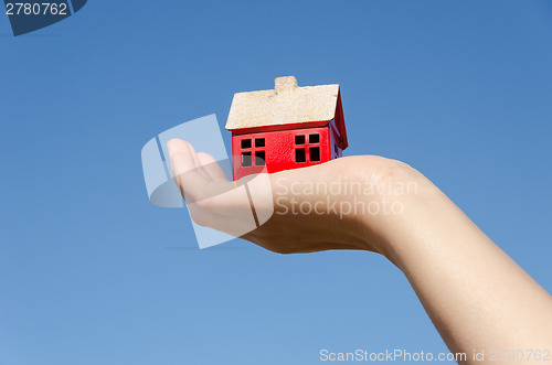 Image of iron house miniature in palm on sky background 