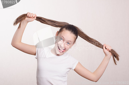 Image of Twelve year old girl holding hair and tongue out