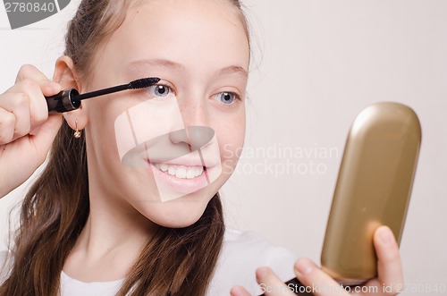 Image of Twelve year old girl paints eyelashes