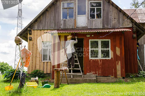 Image of Painter man on ladder paint old wooden house 