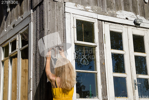 Image of Woman hang horse shoe symbol of luck on wall 