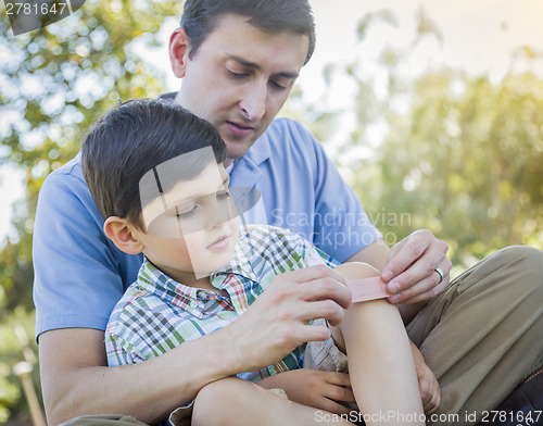 Image of Loving Father Puts Bandage on Knee of Young Son