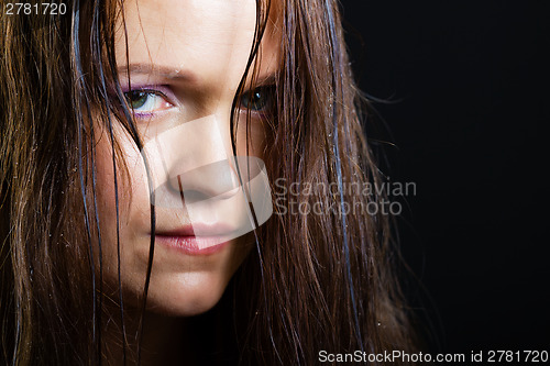 Image of portrait of a sad young girl with long wet hair on a black
