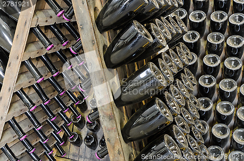 Image of Dusty bottles with brut sparkling wine on wooden rack