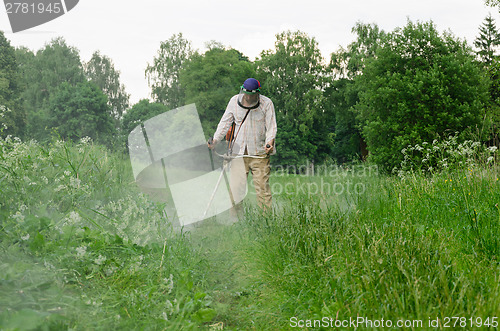 Image of Worker man cut trim mow wet grass after rain 