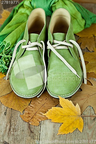 Image of pair of green leather boots, scarf and yellow leaves