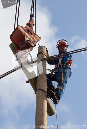 Image of electrician raises the wire on top of an electricity pylon 