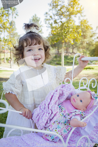 Image of Adorable Young Baby Girl Playing with Baby Doll and Carriage