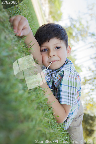 Image of Young Boy Enjoying His Lollipop Outdoors Laying on Grass