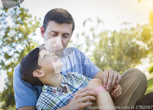 Image of Loving Father Puts Bandage on Knee of Young Son