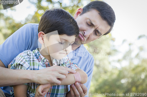 Image of Loving Father Puts Bandage on Elbow of Young Son