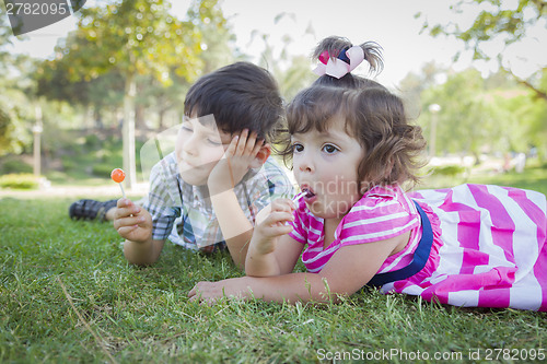 Image of Young Brother and Baby Sister Enjoying Their Lollipops Outdoors