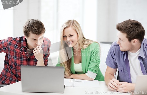 Image of smiling students looking at laptop at school