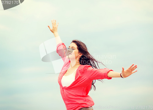 Image of girl with hands up on the beach