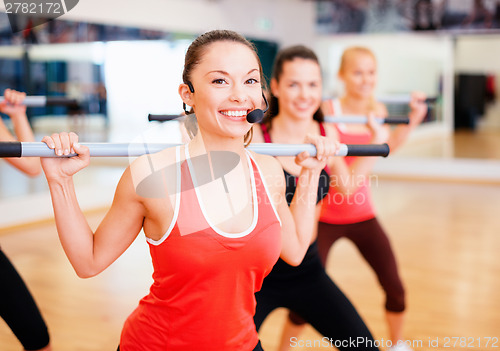 Image of group of smiling people working out with barbells