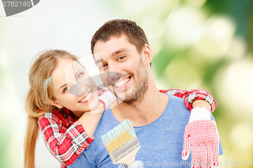 Image of smiling couple covered with paint with paint brush