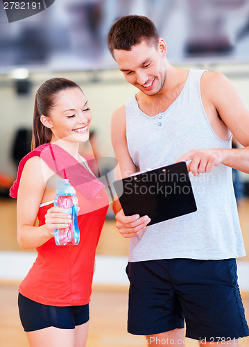 Image of smiling male trainer with woman in the gym