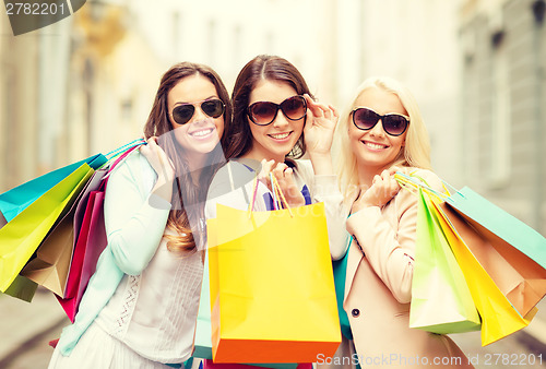 Image of three smiling girls with shopping bags in ctiy