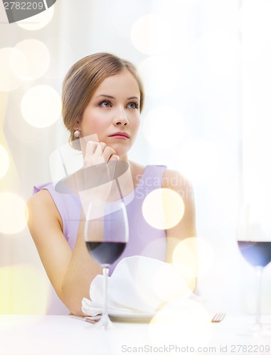 Image of upset woman with glass of whine waiting for date