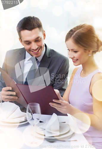 Image of smiling couple with menu at restaurant