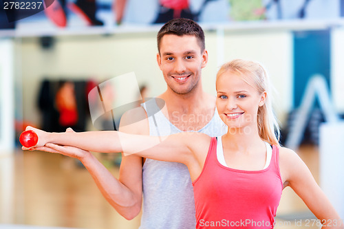 Image of male trainer with woman working out with dumbbell