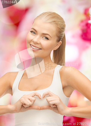 Image of smiling young woman showing heart shape gesture