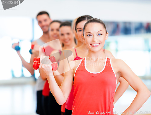 Image of group of smiling people with dumbbells in the gym