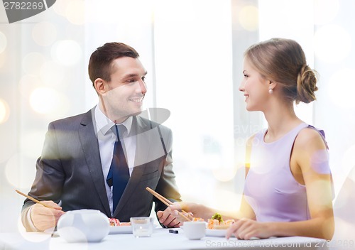 Image of smiling couple eating sushi at restaurant