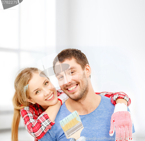 Image of smiling couple covered with paint with paint brush