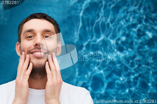 Image of beautiful smiling man touching his face