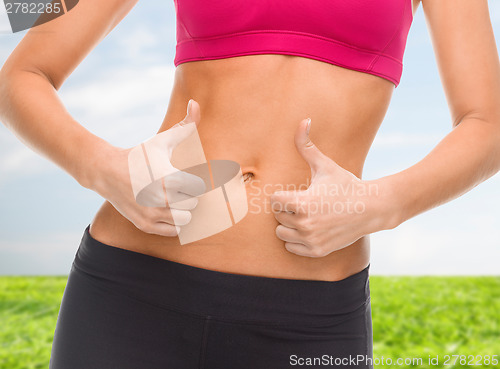 Image of close up of female abs and hands showing thumbs up