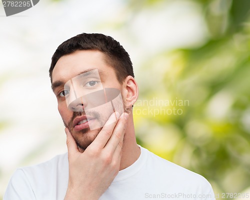 Image of beautiful calm man touching his face