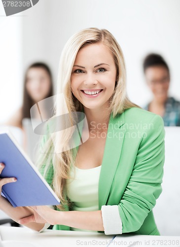 Image of smiling young girl reading book at school