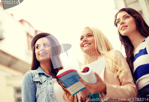 Image of three beautiful girls with tourist book in city