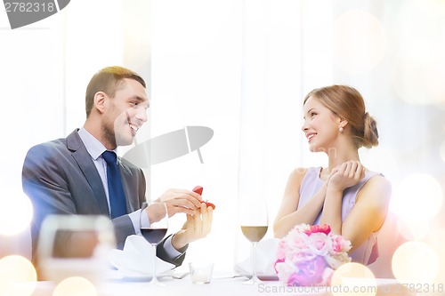 Image of man proposing to his girlfriend at restaurant