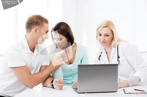 Image of doctor with patients looking at laptop