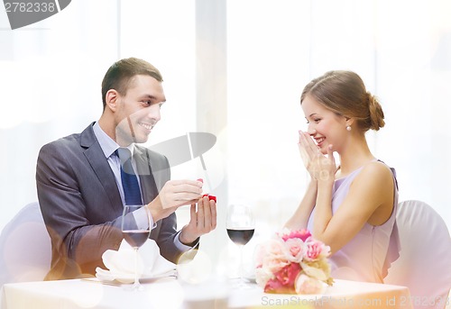 Image of man proposing to his girlfriend at restaurant