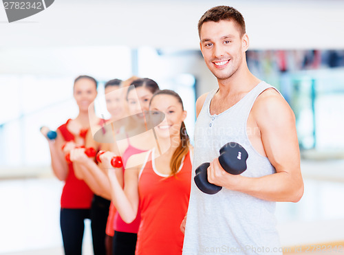 Image of group of smiling people with dumbbells in the gym