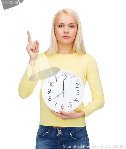 Image of student with wall clock and finger up