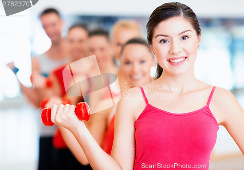 Image of group of smiling people with dumbbells in the gym